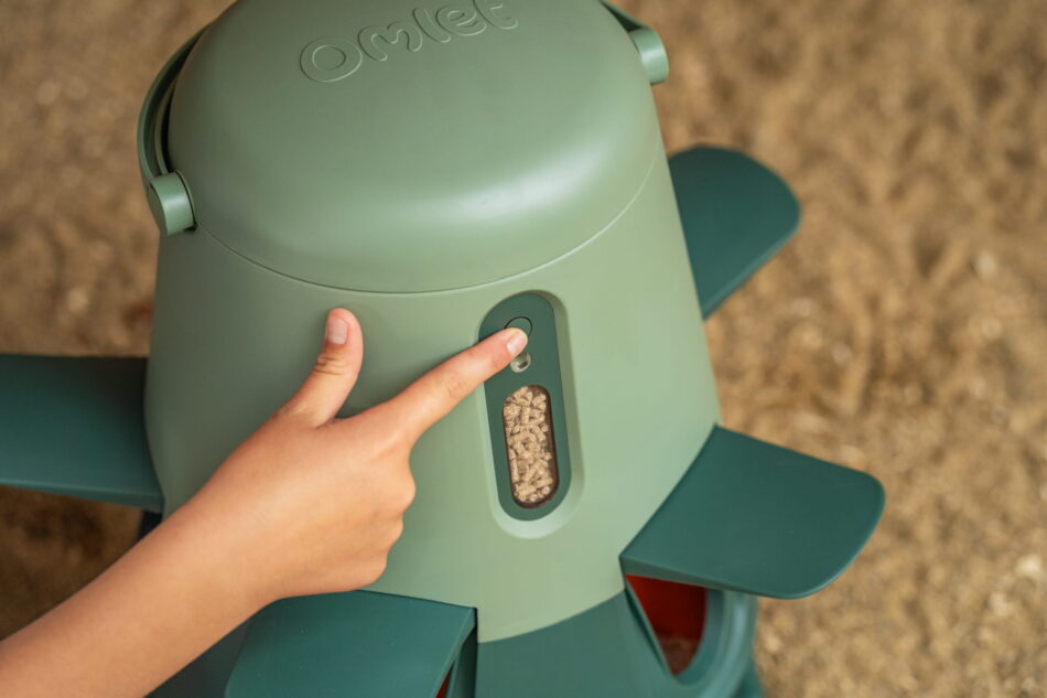 meisje dat op de knop van een Omlet Smart Feeder drukt