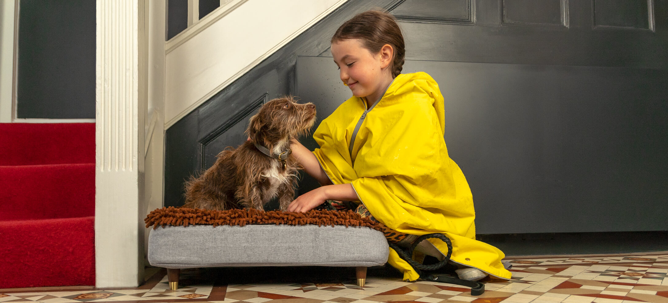 Meisje kijkt naar haar hond op een Omlet Topology hondenmand