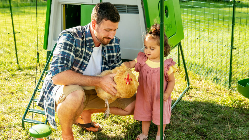 Men en kind houden kip vast bij de Eglu Cube