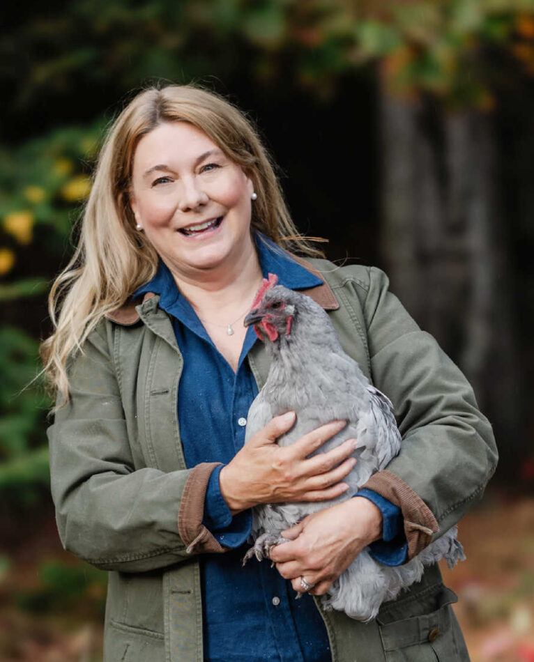 Lisa Steele glimlacht terwijl ze haar kip vasthoudt